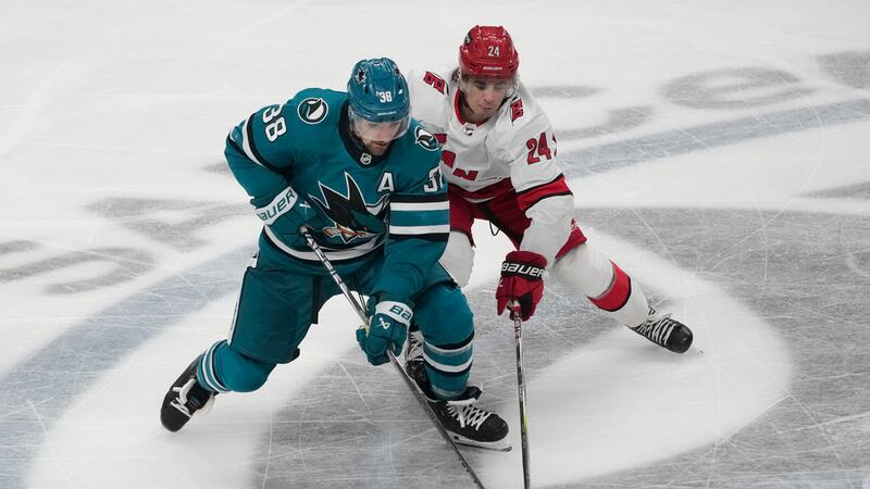 San Jose Sharks defenseman Mario Ferraro (38) reaches for the puck next to Carolina Hurricanes...